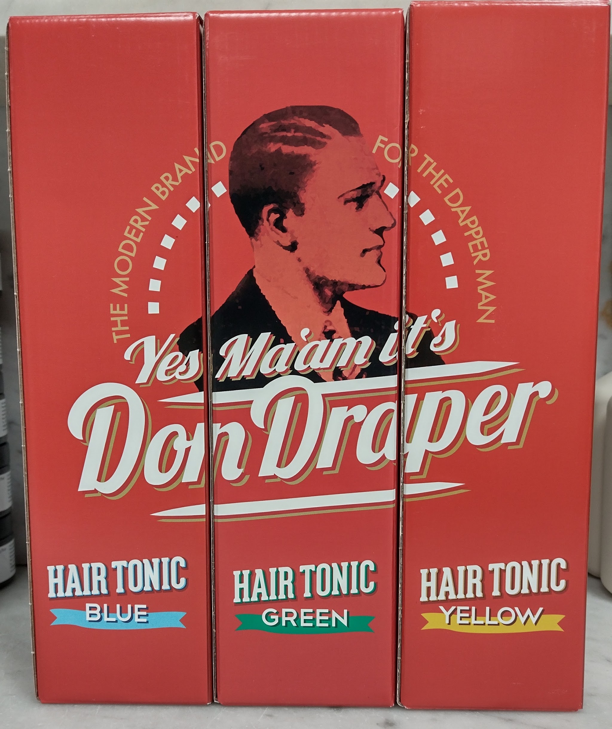 Display met hair tonic van Don Draper in blauw, groen en geel